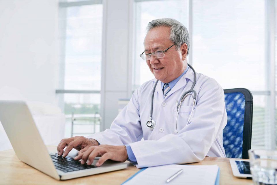 Doctor writes patient notes on laptop