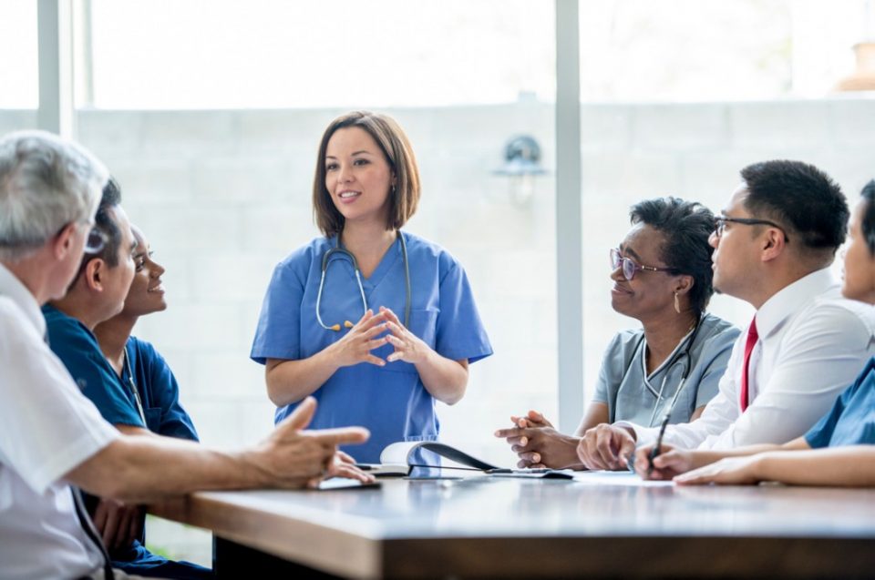 Healthcare professional leading a team discussion at a conference table